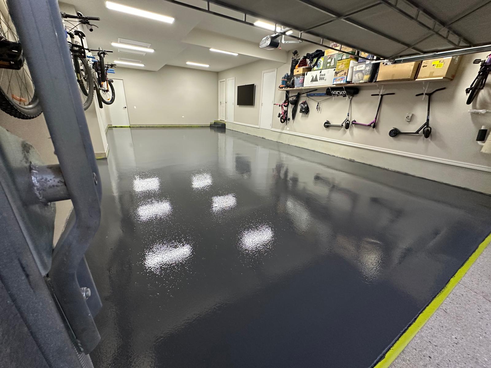 High-gloss charcoal epoxy garage floor reflecting ceiling lights in a Heidelberg triple garage
