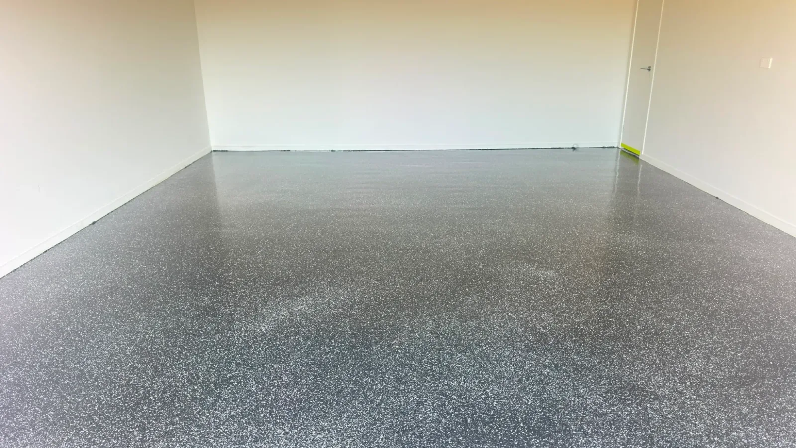 Close-up of the finished flake epoxy garage floor texture in Officer, showing the gloss polyaspartic topcoat